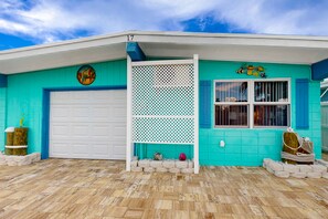 A turquoise house with a white garage door, a decorative lattice, and a window with shutters. - Saylor's Bay | House in Key Colony Beach with ocean views (Key Colony Beach)