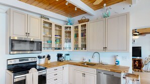 A modern kitchen with white cabinets, a stainless steel oven, a dishwasher, and a wooden countertop. - Saylor's Bay | House in Key Colony Beach with ocean views (Key Colony Beach)