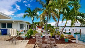 A patio area with outdoor furniture, palm trees, and a view of the water. - Saylor's Bay | House in Key Colony Beach with ocean views (Key Colony Beach)