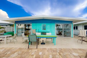A covered patio area with a turquoise-colored wall, a table, chairs, and a grill. - Saylor's Bay | House in Key Colony Beach with ocean views (Key Colony Beach)