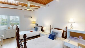 A hotel room with two beds, a wooden ceiling, white walls, and a window with a view of palm trees. - Saylor's Bay | House in Key Colony Beach with ocean views (Key Colony Beach)
