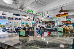 Eine Bar mit einer Marmorplatte, verschiedenen Flaschen und einem Schild mit der Aufschrift 'Best Drunk with a Chingue of Fishing'.