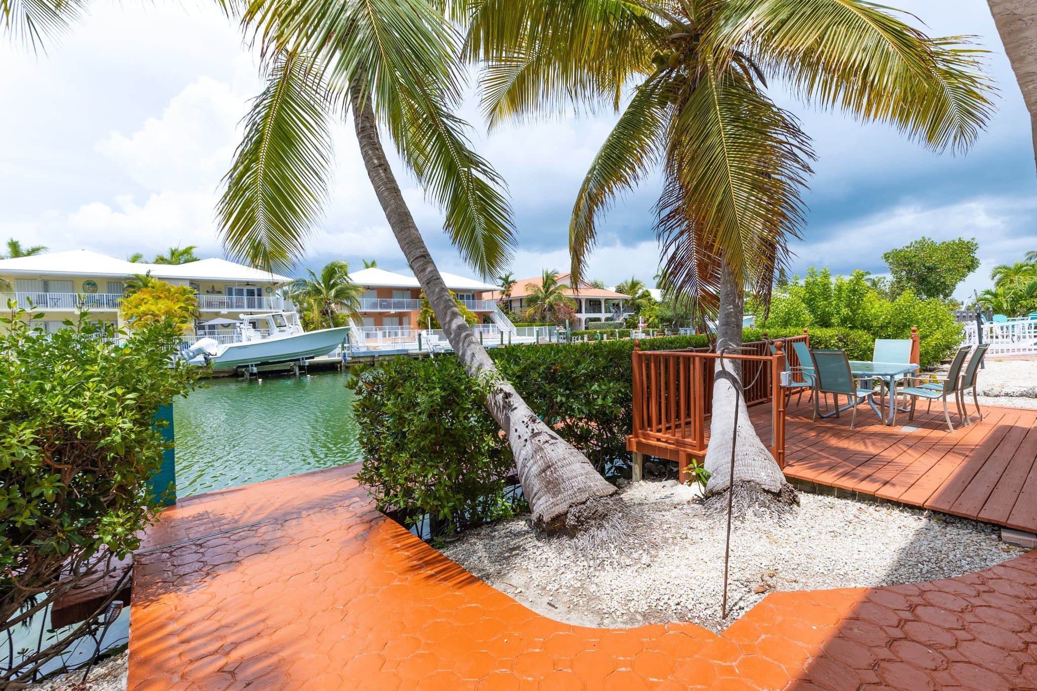 A resort with a pool, palm trees, and a deck with chairs.