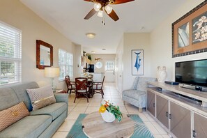 A living room with a sofa, coffee table, TV, and dining area.