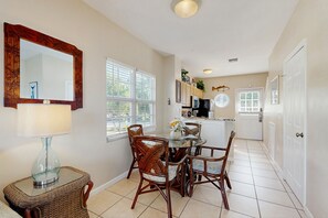 A dining area with a table, chairs, a lamp, and a mirror.