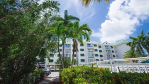 A multi-story hotel with balconies, surrounded by lush greenery and palm trees. - Resort condo with pool & hot tub, private parking (Key West)