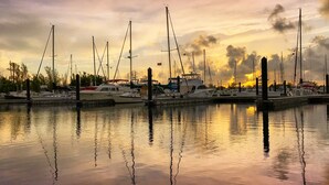 A marina with multiple boats docked, calm water reflecting the boats, and a sunset sky. - Resort condo with pool & hot tub, private parking (Key West)