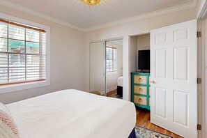 Ein Schlafzimmer mit einem Bett, einem Kleiderschrank, einem Fernseher und einem Fenster mit Jalousien.