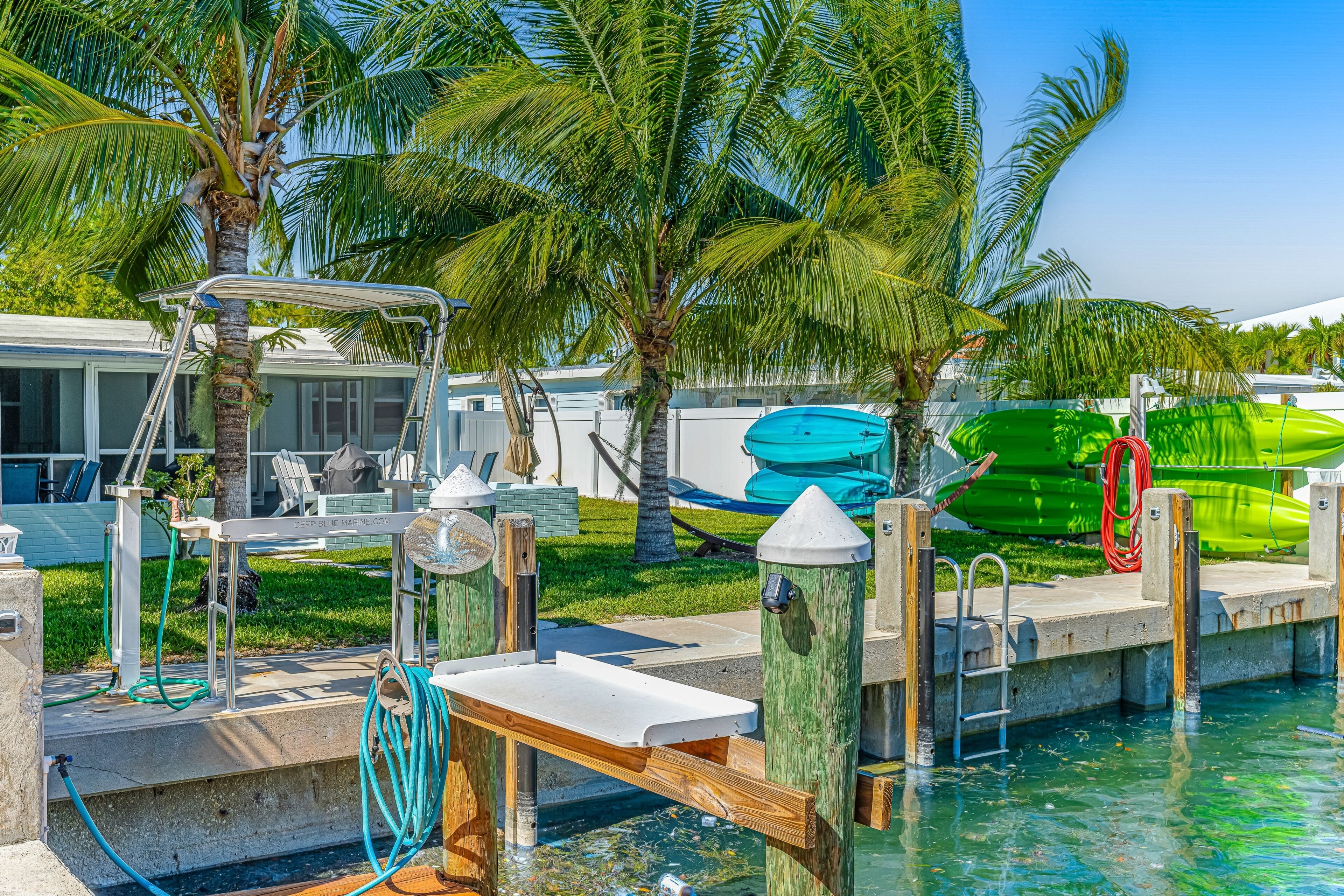 A poolside area with a diving board, a green kayak, and a green paddleboard.