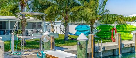 A poolside area with a diving board, a green kayak, and a green paddleboard.