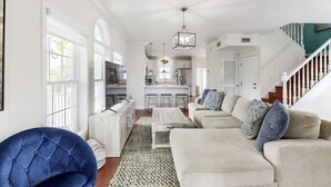 A spacious living room with a large sofa, a blue armchair, and a kitchen in the background. - Waterfront home w/hot tub, gas grill, WiFi, AC, near attractions (Key Largo)