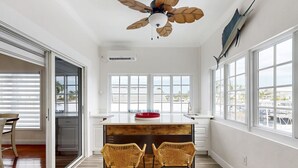 A modern kitchen with a wooden island, two wicker chairs, and a ceiling fan. - Waterfront home w/hot tub, gas grill, WiFi, AC, near attractions (Key Largo)