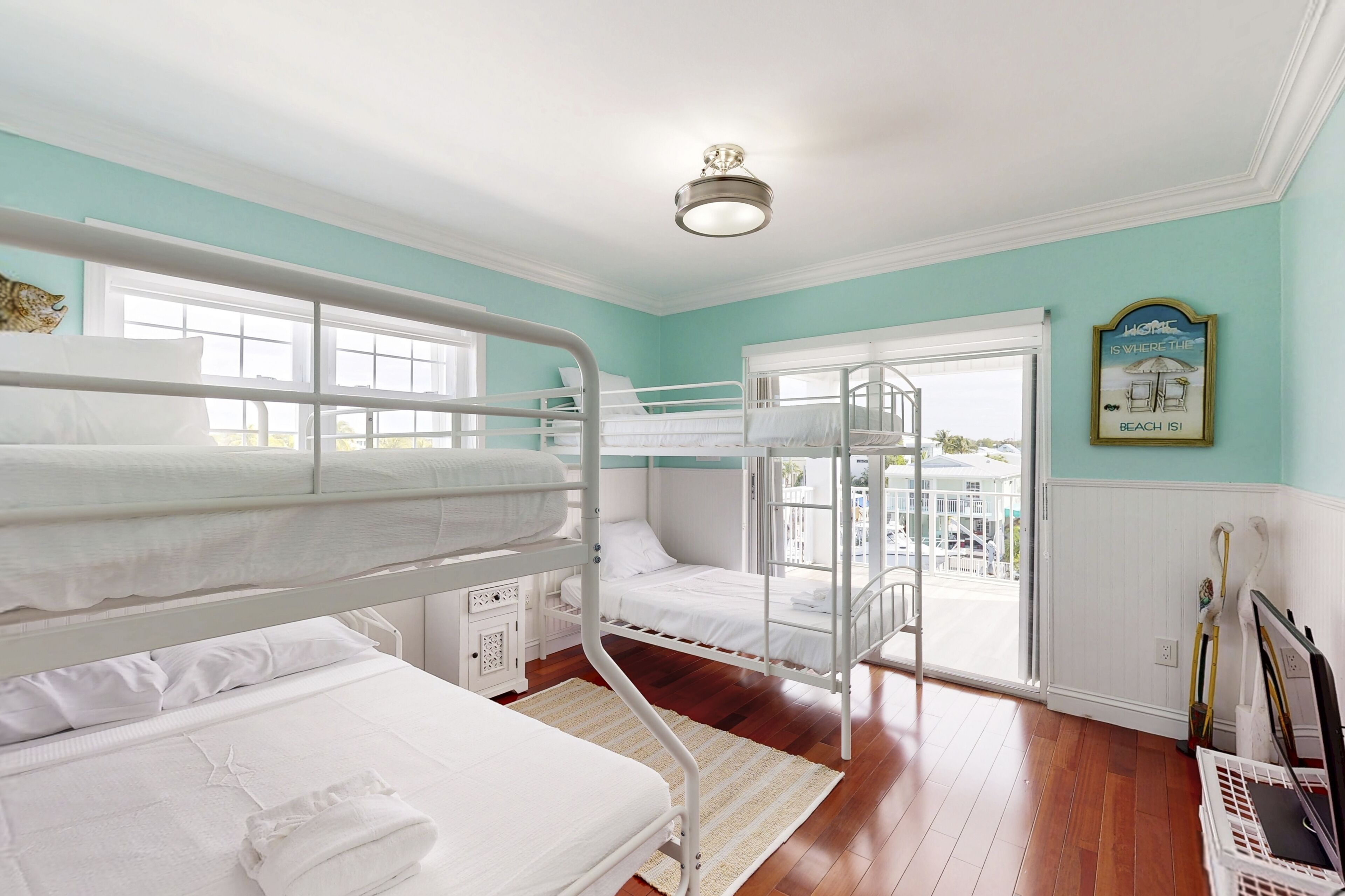 A room with bunk beds, a window, a door leading outside, and a ceiling light fixture.