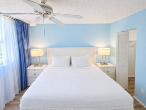 Ein Schlafzimmer mit einem großen Bett, zwei Nachttischen mit Lampen, einem Deckenventilator und einem Kleiderschrank.