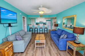 A compact living space with a kitchenette, a ceiling fan, a TV mounted on the wall, and a large mirror. - Sunrise Suites Condo with Balcony - Shared Pool, Hot Tub, Tennis, Free Parking (Key West)