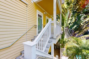 A yellow house with a white staircase and a white railing. - Charming island retreat with balcony, king bed, desk space & dog-friendly vibe (Key West)