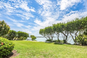 A grassy area with trees and a body of water in the background. - Immaculate oceanfront townhouse with ocean view & private beach access (Duck Key)
