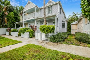 A two-story house with a porch, surrounded by a white picket fence and lush greenery. - Tropical oasis near all the action with central AC & balcony (Duck Key)