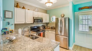 A kitchen with white cabinets, stainless steel appliances, a granite countertop, and a teal wall. - Tropical oasis near all the action with central AC & balcony (Duck Key)