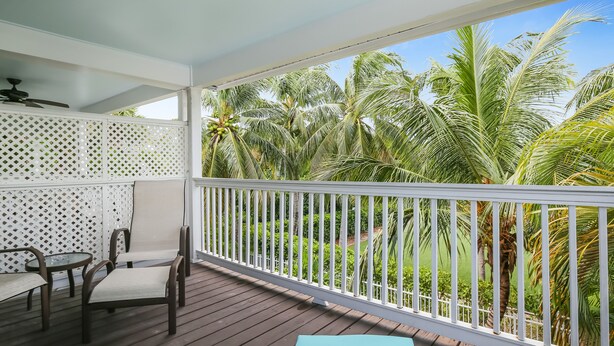A wooden deck with a white railing, a table, and chairs. - Tropical oasis near all the action with central AC & balcony (Duck Key)