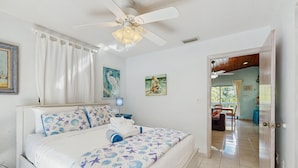 A bedroom with a bed, ceiling fan, and artwork on the walls. - Dog friendly Florida Keys Home with Grill, Patio & Fully Equipped Kitchen (Key Largo)