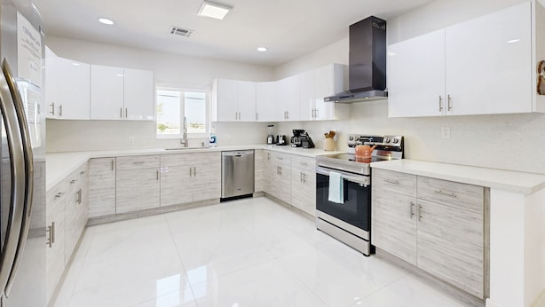 Uma cozinha moderna com armários brancos, eletrodomésticos de aço inoxidável e uma ilha central.