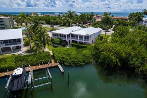 A coastal property with a large house, dock, and surrounding greenery. - Coastal Waterfront Villa with pool, paddleboards & tennis courts (Marathon)