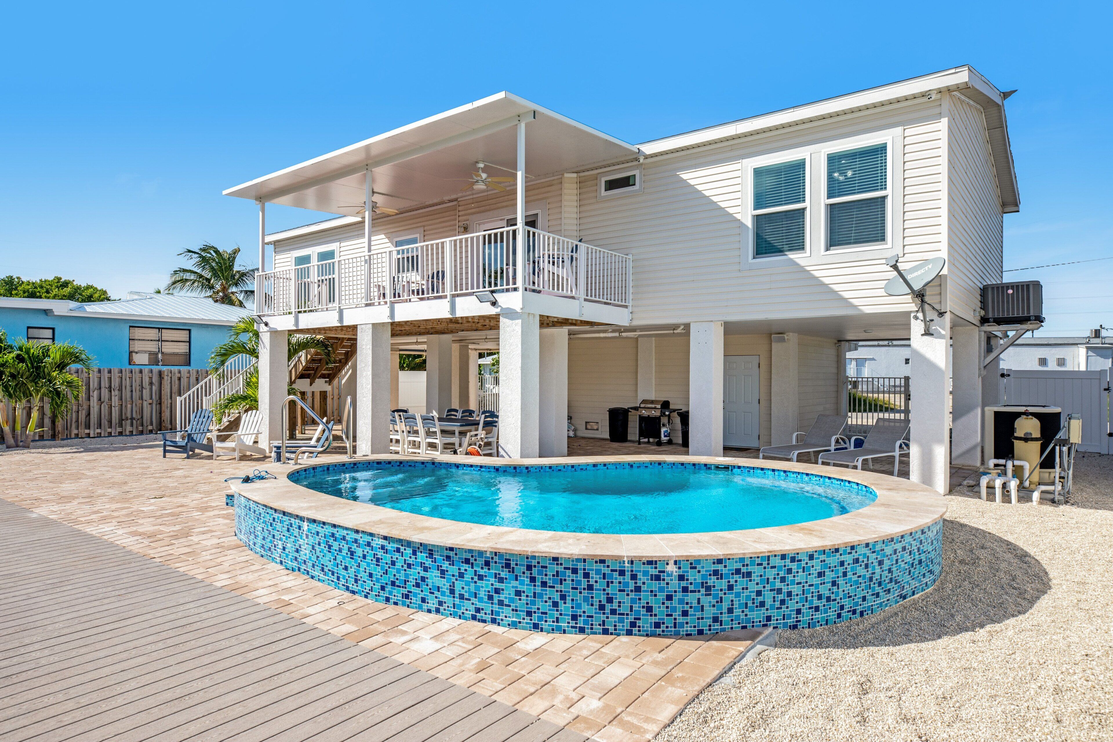 Ein zweistöckiges Haus mit Swimmingpool, überdachter Terrasse und einer Holzterrasse.