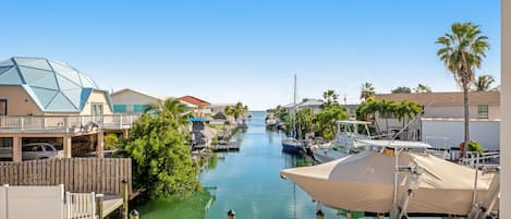A marina with boats docked, a clear sky, and buildings with balconies.
