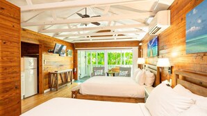 Une chambre de style cabane en bois, avec deux lits, un bureau, une télévision et une vue sur la verdure grâce à de grandes fenêtres.