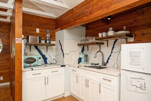 A kitchen with wooden beams, white cabinets, a microwave, a blender, and a refrigerator. - Studio with pool - 1 block to Duval St shops/restaurants & 2 blocks to beach (Key West)