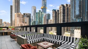 A rooftop terrace with a modern seating area, a dining table, and a city skyline view. - Chic Apartment Near Crown Casino,pool, Gym & Views (Melbourne)