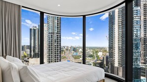 A bedroom with a large bed, a curved window, and a city view. - Chic Apartment Near Crown Casino,pool, Gym & Views (Melbourne)