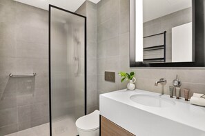Ein modernes Badezimmer mit Duschkabine aus Glas, einem weißen Waschbecken und einem Spiegel über dem Waschtisch.