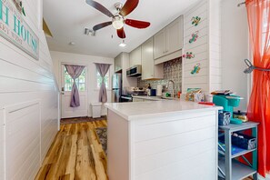 A modern kitchen with white cabinetry, a central island, and a ceiling fan. - Colorful home in private community with resort pool & hot tub, on-site golf (Key West)