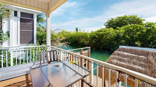Ein Balkon mit Tisch und Stühlen mit Blick auf einen Fluss und üppiges Grün.