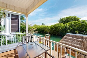 Ein Balkon mit Tisch und Stühlen mit Blick auf einen Fluss und üppiges Grün.