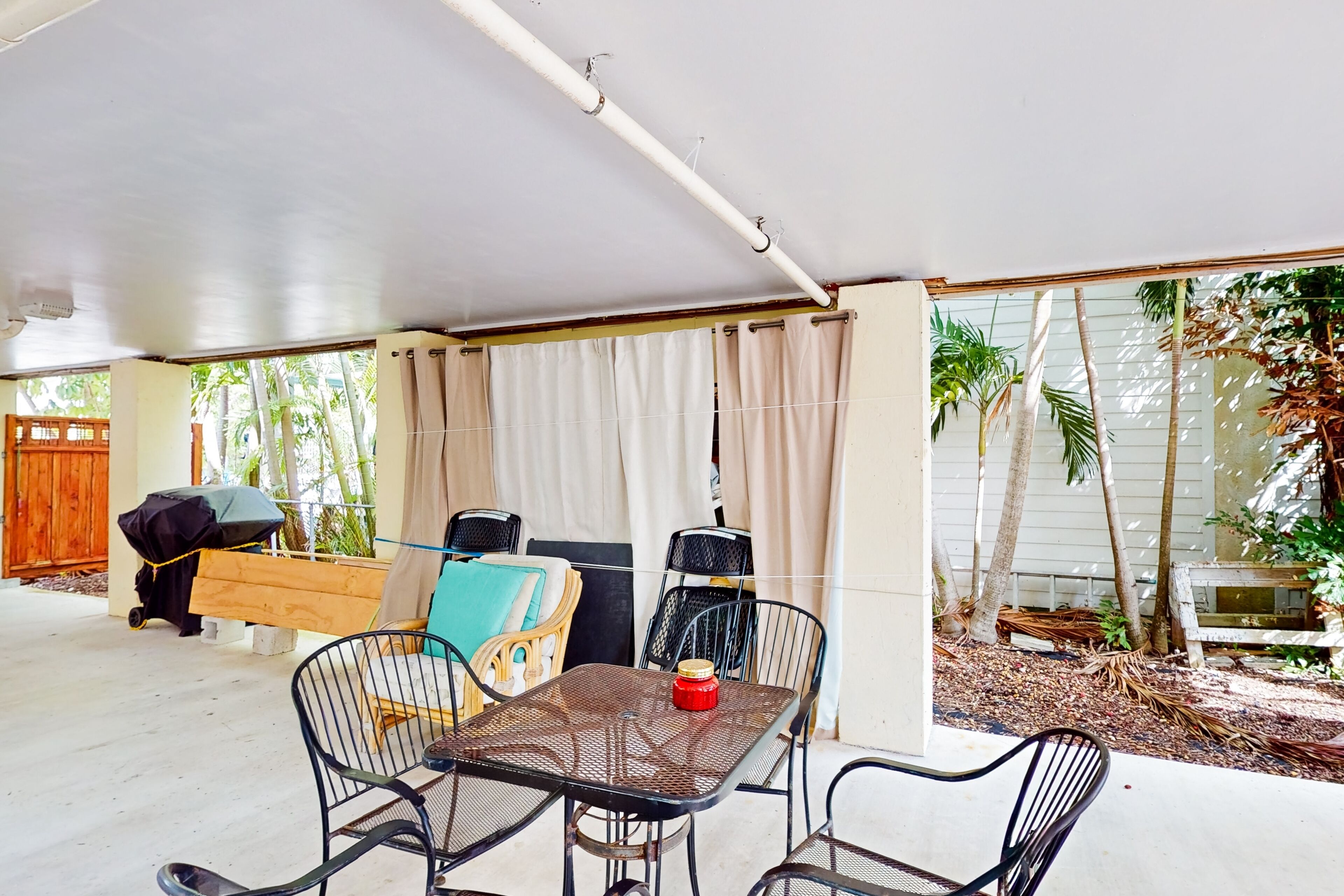 An outdoor patio with a covered seating area, including a table and chairs, and a grill.