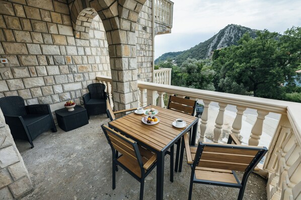 Eine Außenpatio mit Steinmauern, einem Holztisch und Stühlen mit Blick auf eine Berglandschaft.
