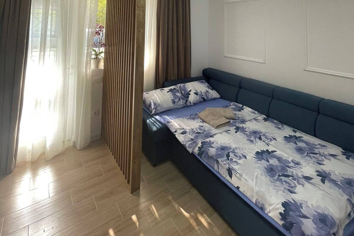 Une chambre à coucher avec un lit, des rideaux, une cloison en bois et un luminaire au plafond.