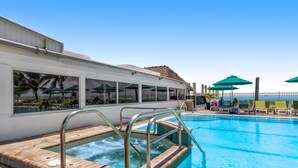 Een zwembad met een jacuzzi, ligbedden en parasols.