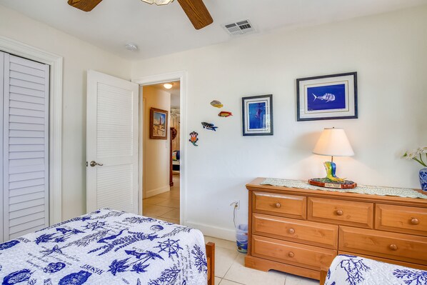 Une chambre à coucher comprenant un lit, une commode et des éléments de décoration murale, notamment des tableaux encadrés et des motifs représentant des poissons.