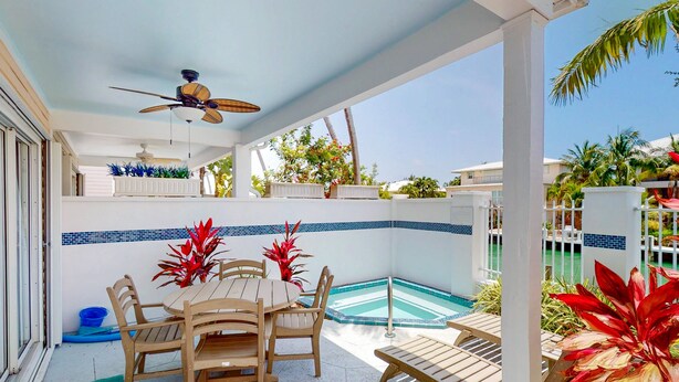 A covered outdoor area with a pool, wooden furniture, and potted plants. - Enchanting waterfront townhouse with balcony, mini oasis pool, & washer/dryer (Duck Key)