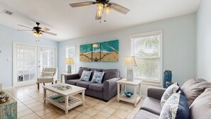 A living room with a grey sofa, a coffee table, a ceiling fan, and a painting on the wall. - Charming home close to the ocean with pool, outdoor dining area and grill (Marathon)