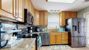 A kitchen with wooden cabinets, stainless steel appliances, granite countertops, and a built-in oven. - Charming home close to the ocean with pool, outdoor dining area and grill (Marathon)