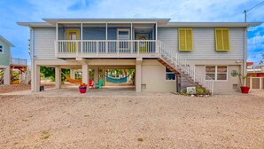 A two-story house with a balcony, a covered porch, and a staircase leading to the upper floor. - Charming home close to the ocean with pool, outdoor dining area and grill (Marathon)