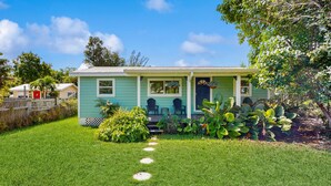 Ein eingeschossiges Haus mit Veranda, kleinem Garten und blauem Himmel.