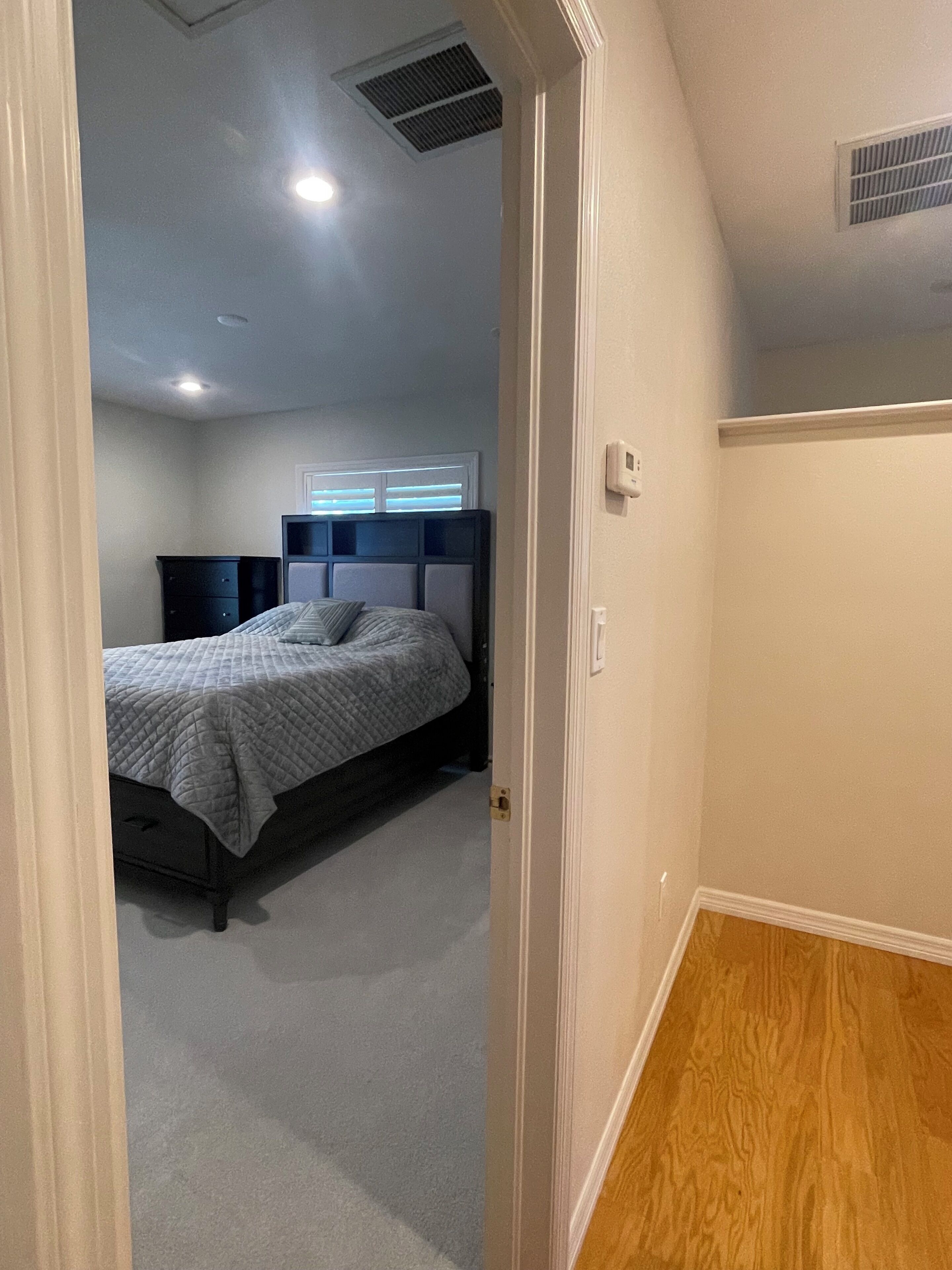 Een slaapkamer met een bed, een dressoir en een raam met jaloezieën.