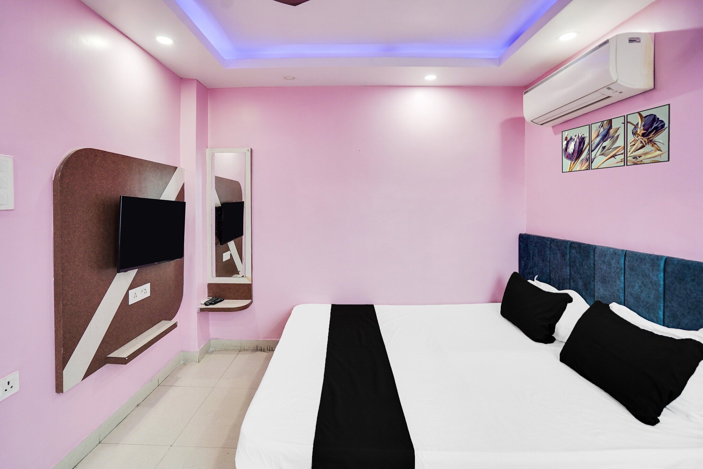 A bedroom with a bed, a TV, a mirror, and an air conditioner.