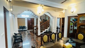 A spacious dining area with a marble floor, a round table with chairs, and a staircase in the background. - Spacious, fully air-conditioned 4-bedroom ensuite home (Perumbavoor)